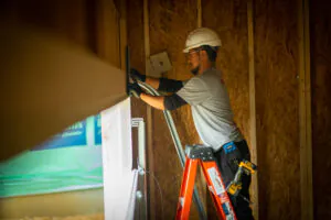 Worker installing materials on ladder