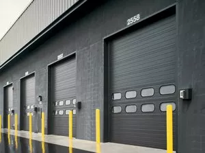 Row of black commercial garage doors on the side of a warehouse building.