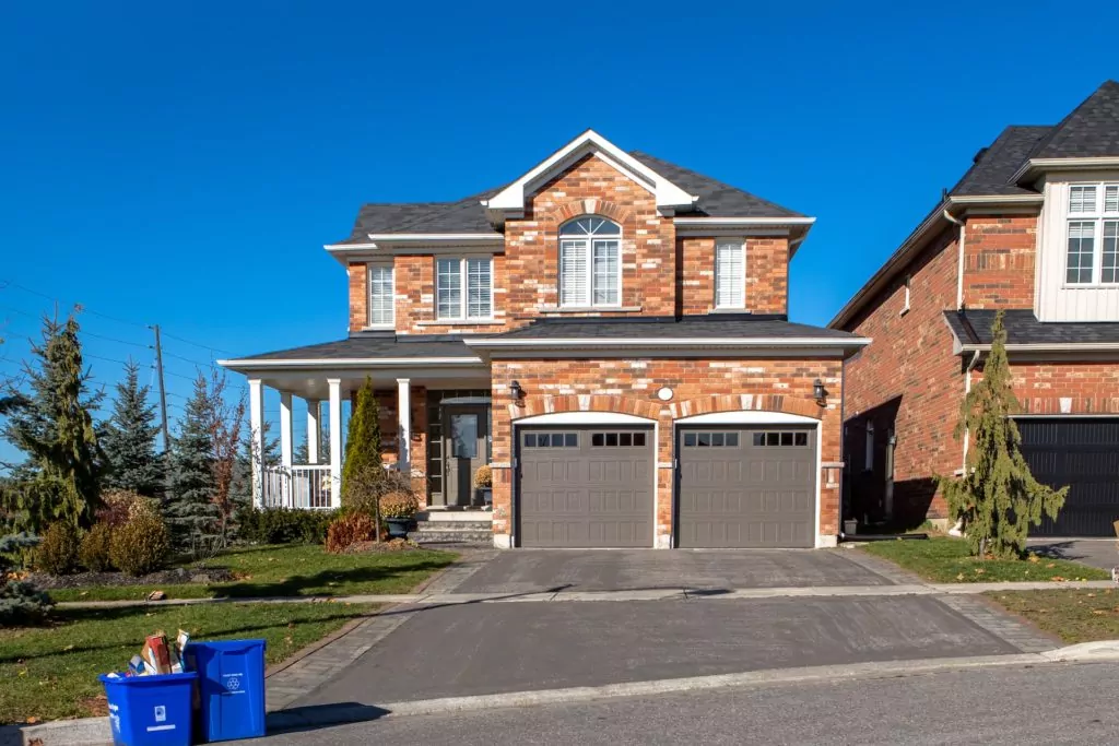 Residential garage doors, traditional style, in dark gray on a large brick home.